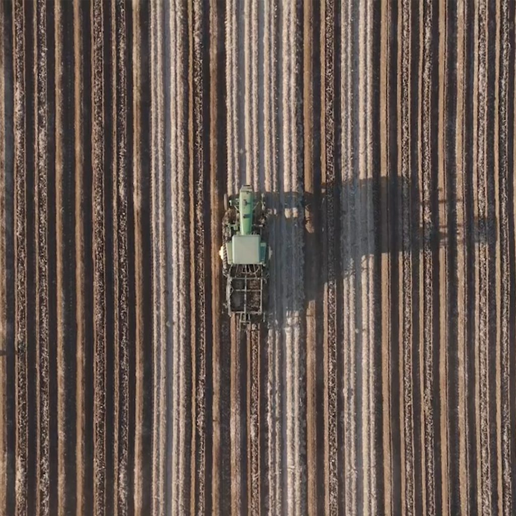 Overhead drone shot of a tractor in a freshly tilled field